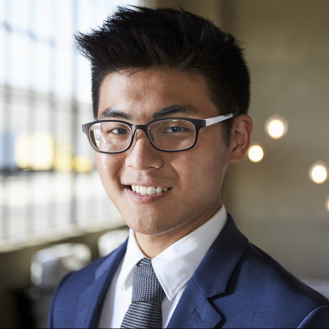 Young Asian businessman smiling to camera, head and shoulders